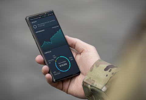 A hand holding a mobile phone with Schwab Intelligent Portfolios on the screen.